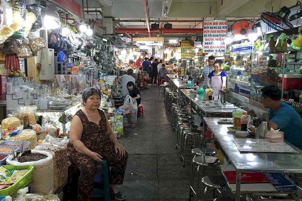 A bustling food court inside An Dong Market with its menu board in Vietnamese 